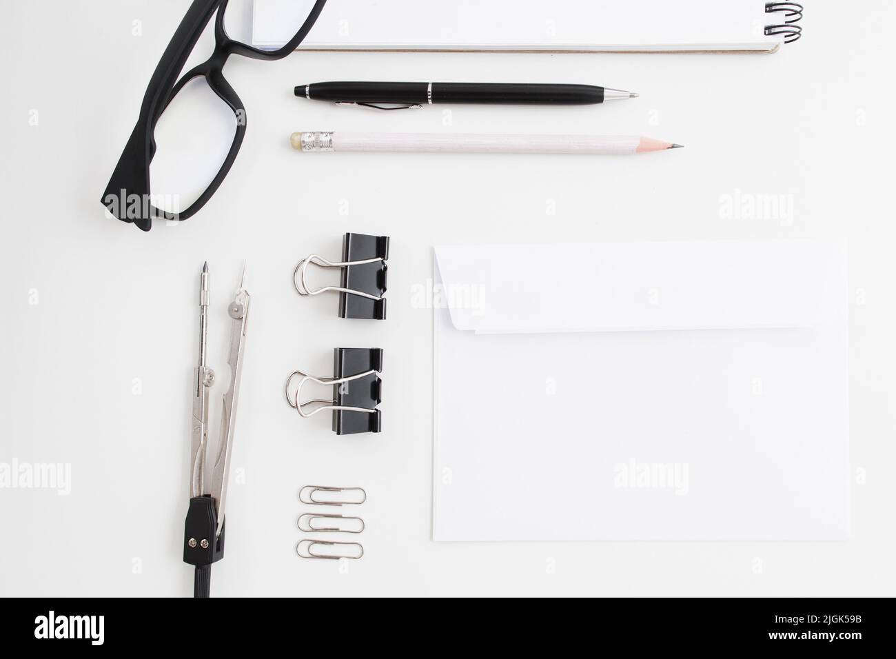 Blocco note vuoto con clip, penna e occhiali a disposizione piatta Foto Stock