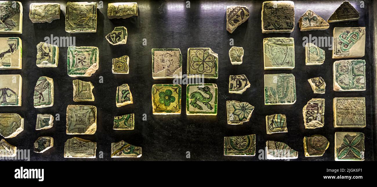 Piastre medievali rotte e intatte decorate con motivi di uccelli e fiori sono disposte in una vetrina nel Palazzo Papale di Avignone, Francia. Foto Stock