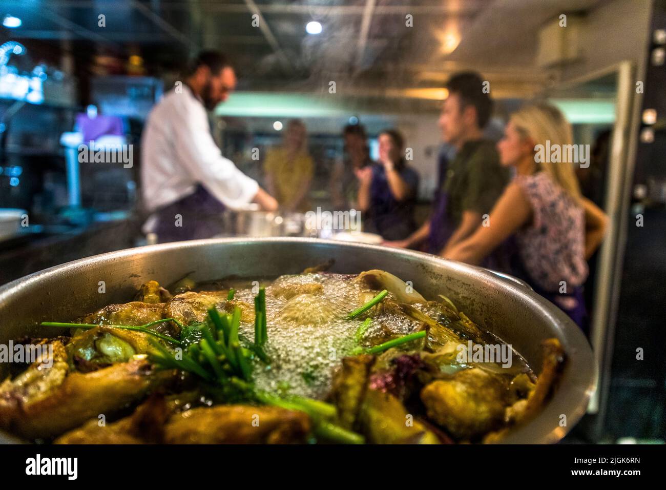 Pezzi di verdure dorati in una pentola di brodo con cipollotti verdi spiccano in primo piano nel corso di cucina di Jon Chiri al ristorante "Cuisine Centr'Halles" nella sala del mercato di Avignon, Francia. Cucinare e mangiare qui avvengono in uno spazio molto ristretto; tutti gli ingredienti provengono dalle bancarelle del mercato circostante, con la freschezza come asso nella manica. Foto Stock