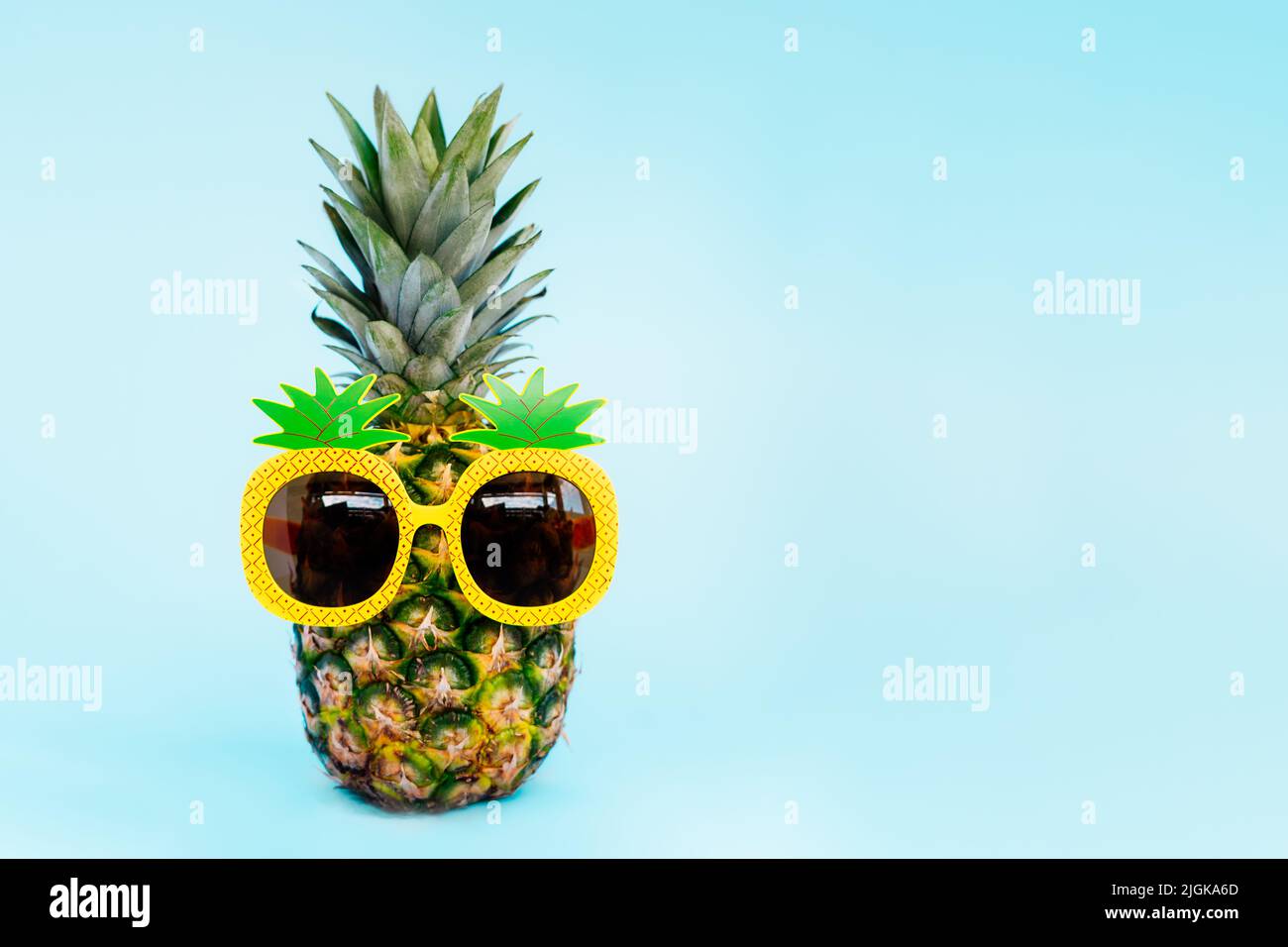 Ananas divertente in un bicchiere di ananas a forma di sfondo blu. Estate in stile tropicale sulle vibrazioni della spiaggia. Frutta esotica. Resort vacanza crea Foto Stock
