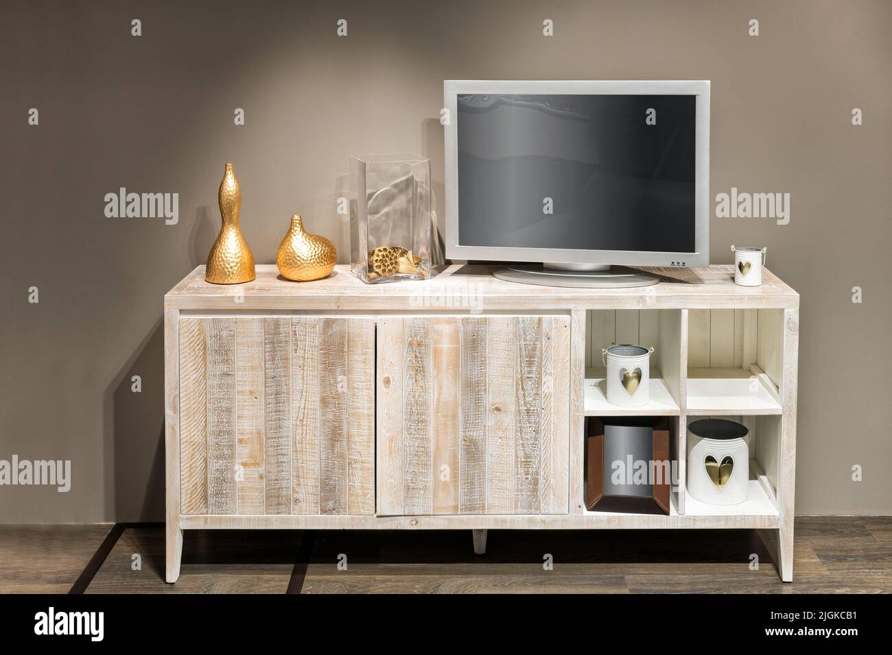 Varie decorazioni eleganti e televisione con schermo vuoto posto sul cabinet contro le pareti beige nel soggiorno Foto Stock