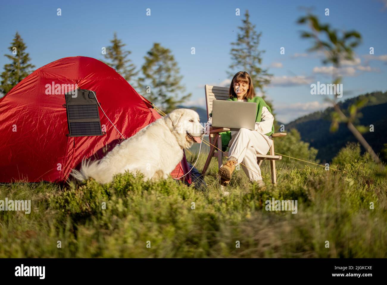 Donna lavora su un computer portatile al campeggio in montagna Foto Stock