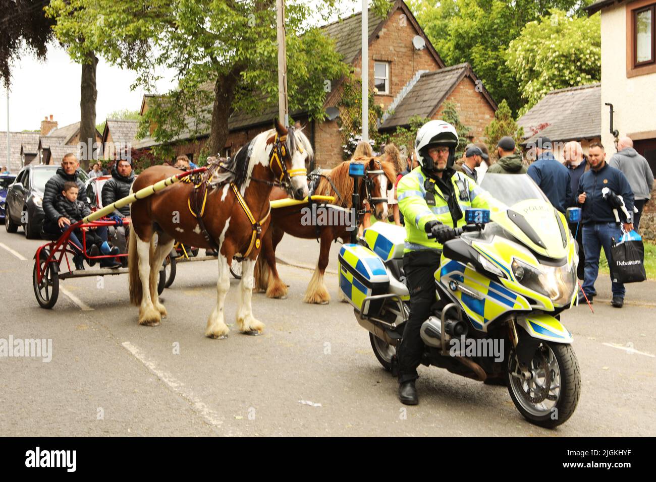 Una motocicletta della polizia e due cavalli che tirano le trappole lungo la strada, Appleby Horse Fair, Appleby a Westmorland, Cumbria Foto Stock
