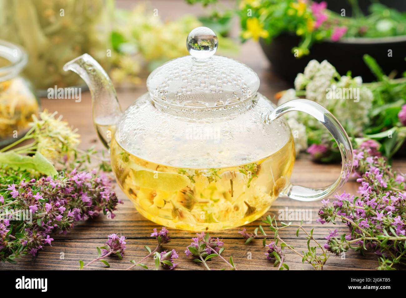 bollitore di tè in vetro di sano tè alle erbe, timo, fiore di tiglio, erba di St Johns, yarrow, camomilla, calendula erbe medicinali su tavola di legno. Opzioni Foto Stock