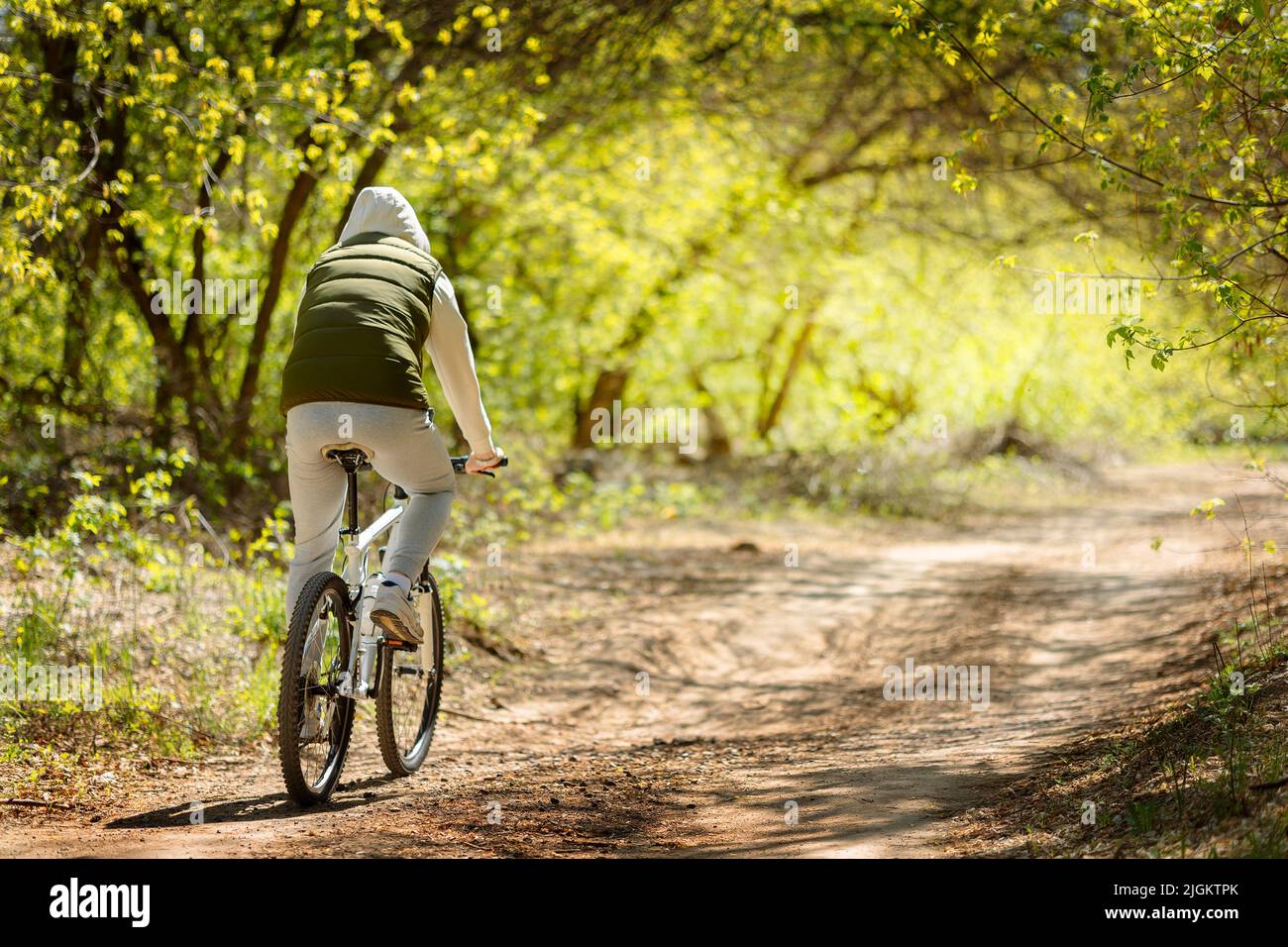 L'uomo in bicicletta passa attraverso il parco fiorito di primavera in giornata di sole. Foto di alta qualità su giri in bicicletta attraverso il parco fiorito di primavera in giornata di sole Foto Stock