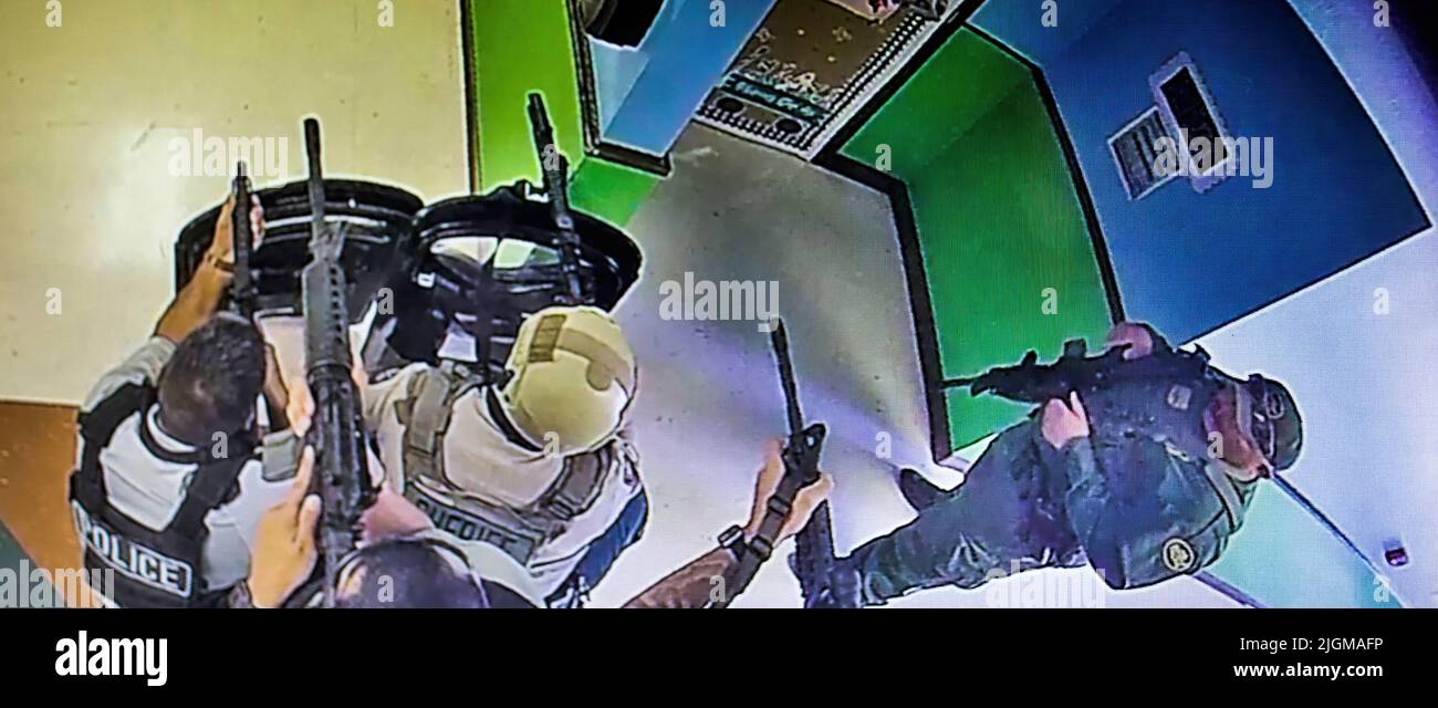 Una cornice di un video di sorveglianza della scuola mostra più poliziotti in attesa in un corridoio alla scuola elementare Robb armati di fucili e almeno uno scudo balistico protettivo. Questo è stato 19 minuti dopo aver ricevuto una chiamata 911 dalla scuola. La polizia ha aspettato quasi un'ora e mezza prima di entrare nella stanza della scuola dove si trovava il cannoniere. (Foto: Archivio investigativo di Uvalde) Foto Stock