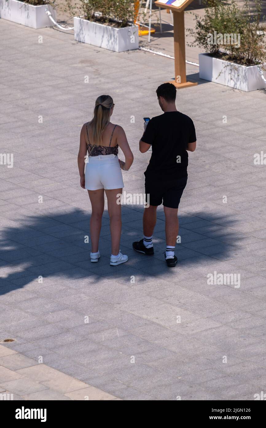 Barcellona, Spagna. 11th luglio 2022. Una coppia turistica è visto consultare il loro dispositivo mobile sotto l'ombra di una palma sulla spiaggia di Sant Sebantian. Seconda ondata di calore estremo che può superare i 44 gradi Celsius in alcune regioni della Spagna. La Catalogna, attualmente al livello uno e dopo settimane di accumulo di alte temperature e di poca pioggia, soffrirà questa settimana alcuni giorni di temperature al di sopra di quanto è solito per queste date Credit: SOPA Images Limited/Alamy Live News Foto Stock
