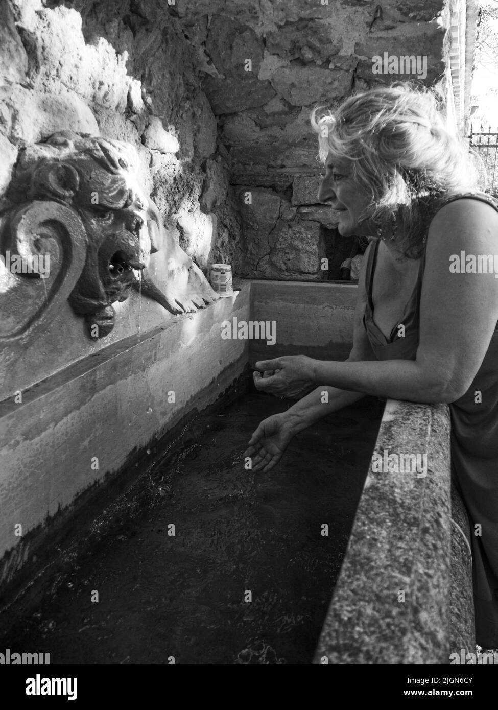 Donna annaffiatura e lavaggio su un pubblico di Foutain a Castell'Arquato Italy.pure e prezioso per la natura. Shot di mani tenute fuori per catturare un flusso d'acqua Foto Stock
