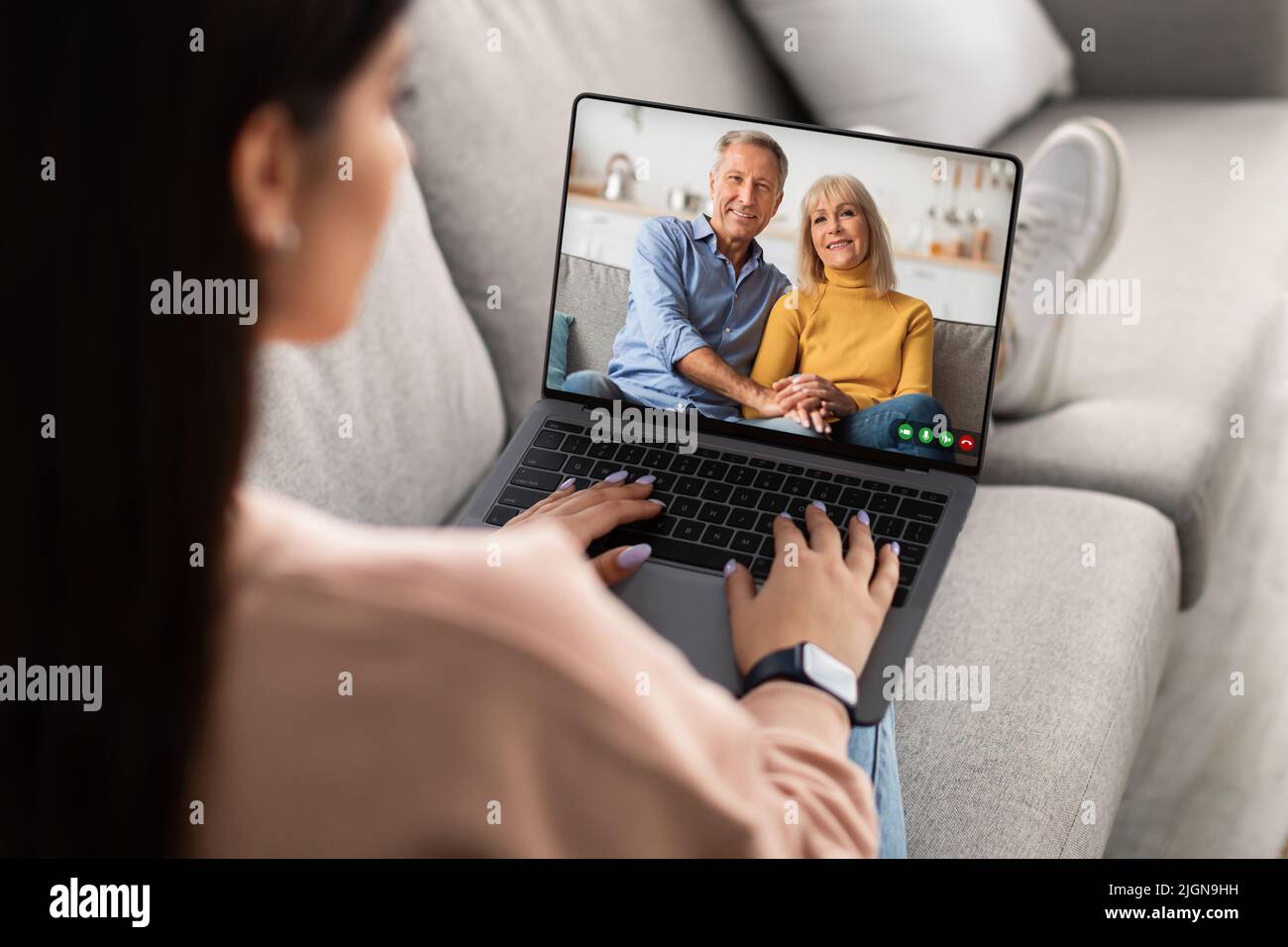 Riunione remota. Giovane donna che ha una videochiamata con i genitori anziani sul laptop Foto Stock