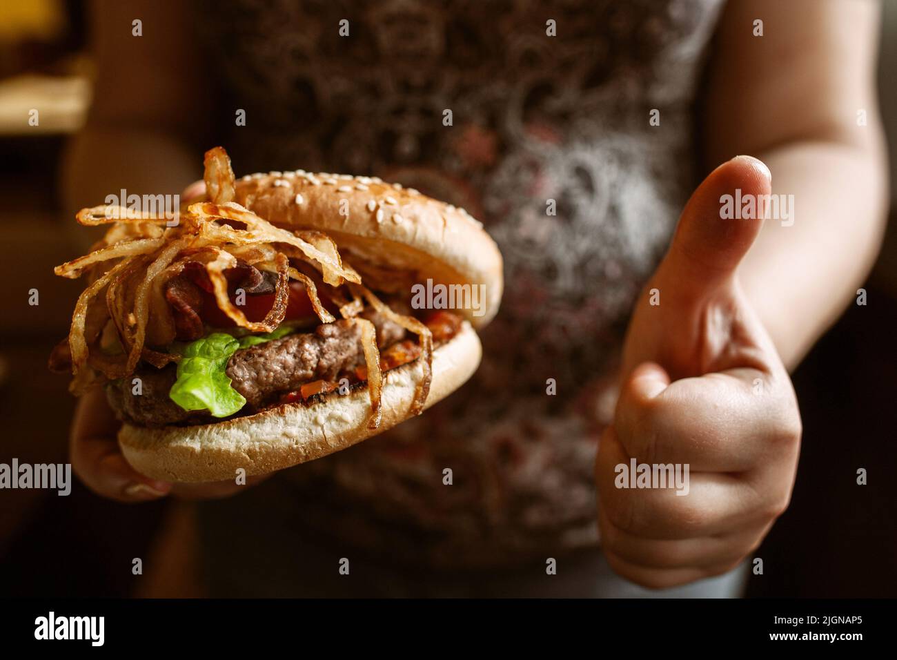 Donna incinta irriconoscibile godere il suo hamburger Foto Stock