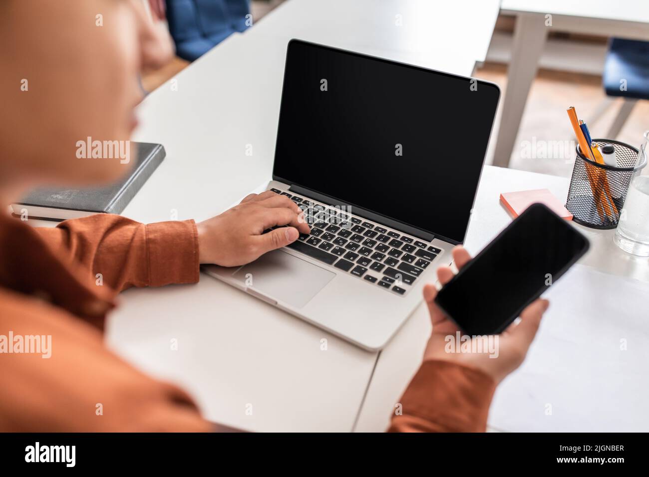 Corto di uomo d'affari giapponese che usa il laptop e il cellulare in ufficio Foto Stock