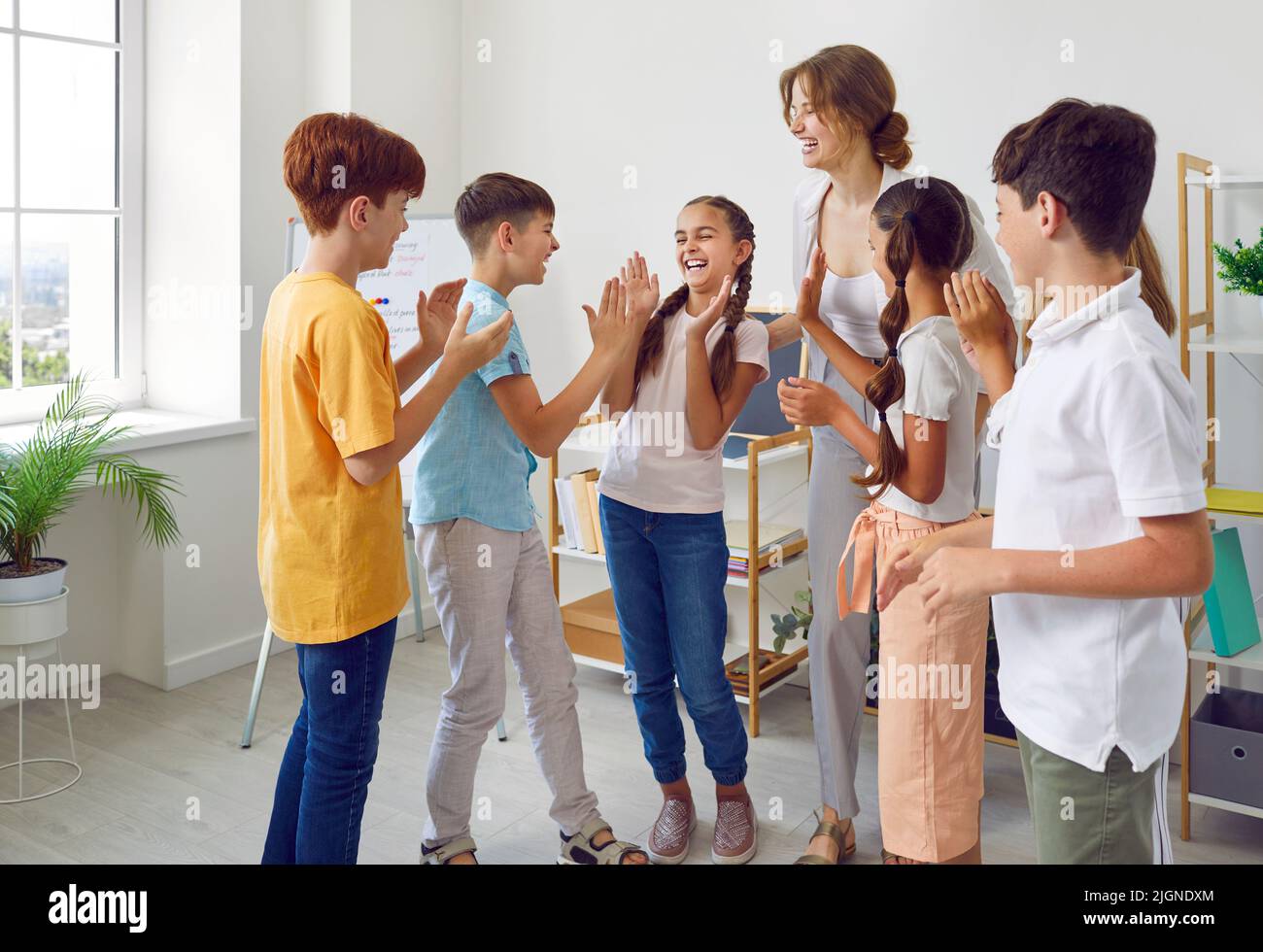 Divertenti scolari e la loro insegnante femminile positiva giocare divertenti giochi in lezione creativa. Foto Stock