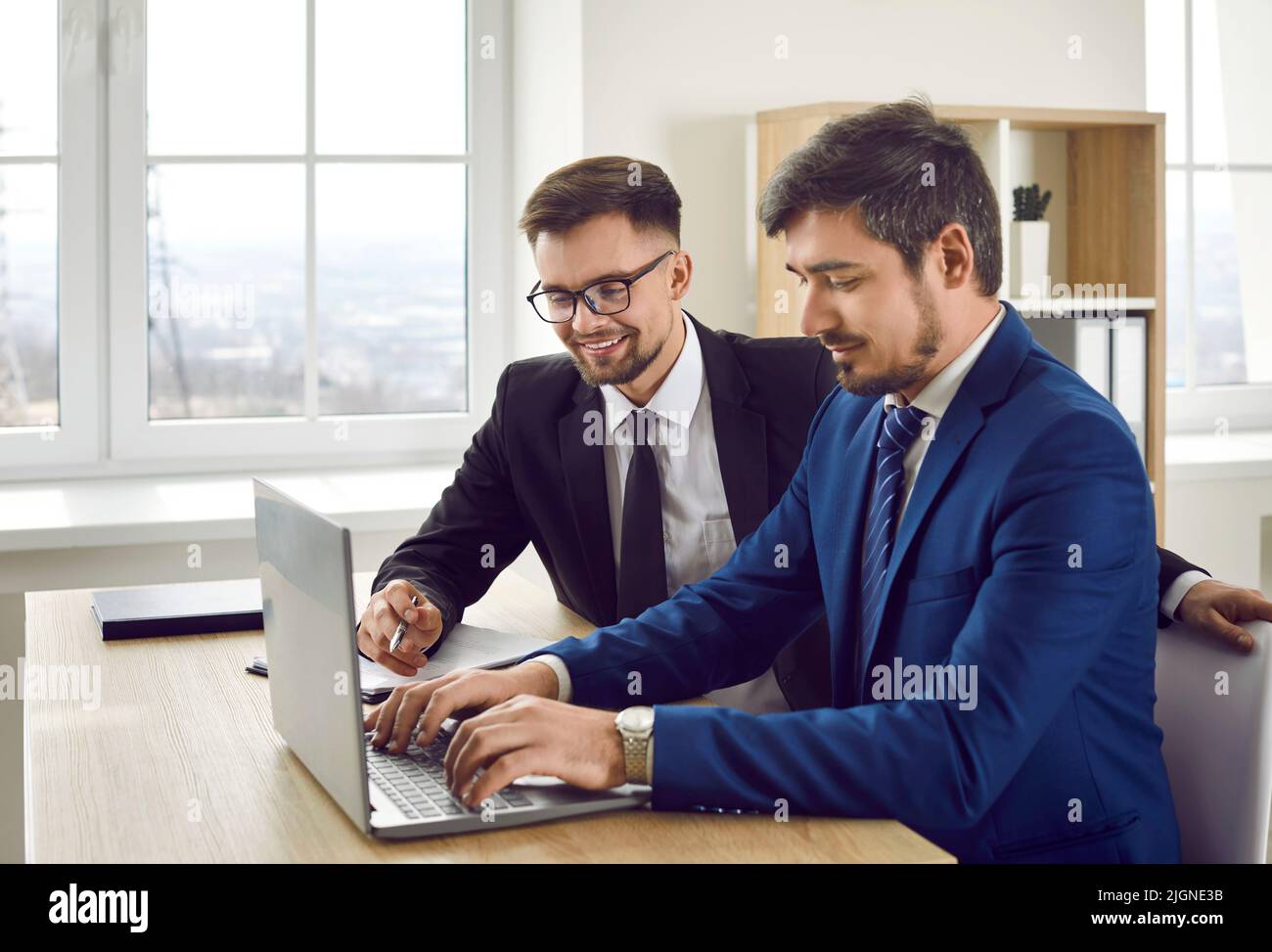 Giovane uomo caucasico positivo che lavora con il laptop creare la presentazione si siede alla scrivania d'ufficio Foto Stock