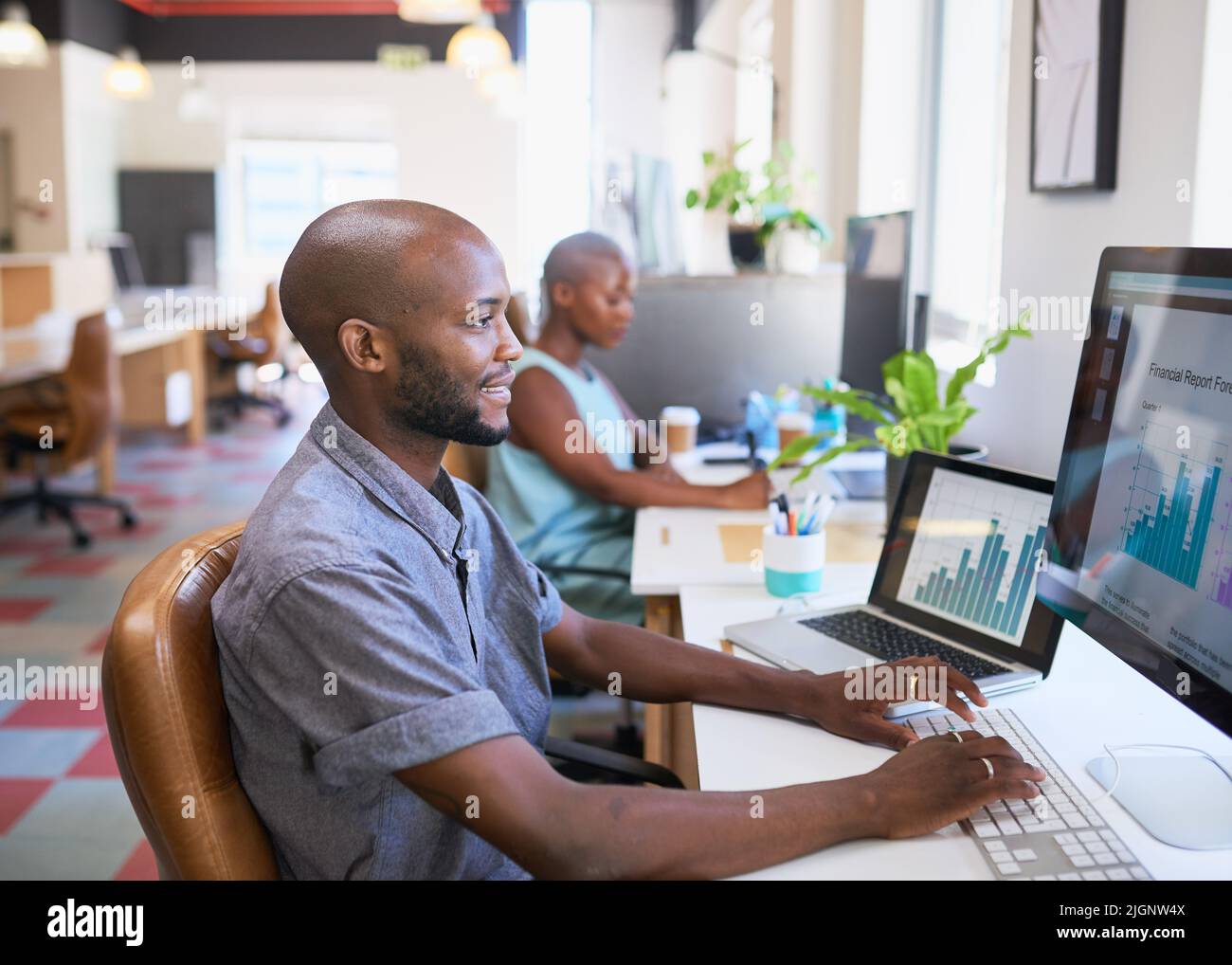 Un uomo d'affari nero lavora alla sua scrivania d'ufficio su un rapporto finanziario con grafici Foto Stock