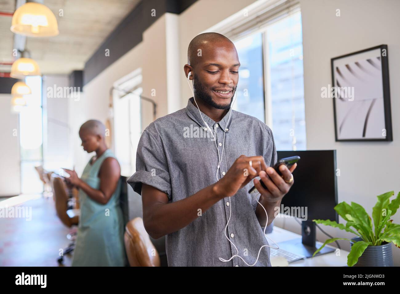 Un uomo nero si connette a una chiamata di riunione remota con gli auricolari in ufficio Foto Stock