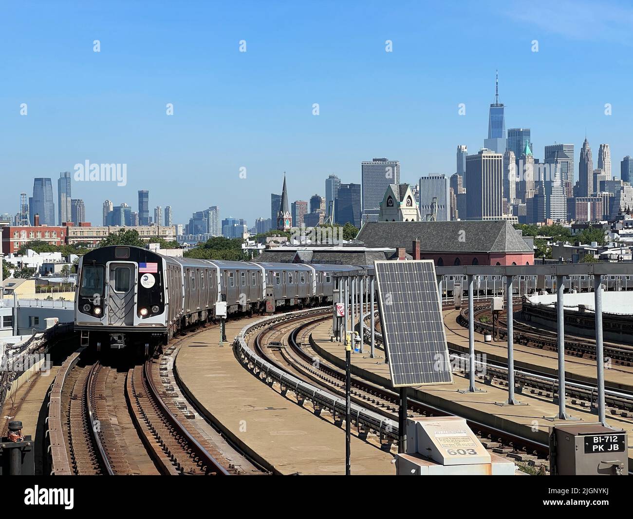 F linea ferroviaria che arriva alla stazione metropolitana di Smith Ninth Street con una vista chiara dello skyline di Lower Manhattan. Foto Stock