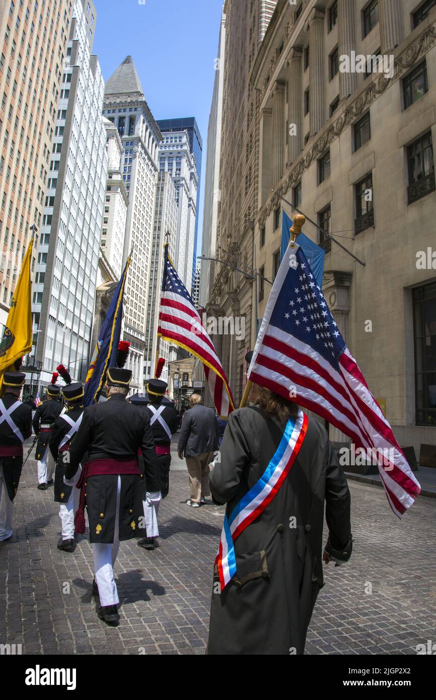 Gli uomini con bandiere americane che indossano uniformi della guerra rivoluzionaria marciano su Broad Street nello storico quartiere finanziario di Lower Manhattan il giorno dell'Indipendenza, luglio 4th. Foto Stock