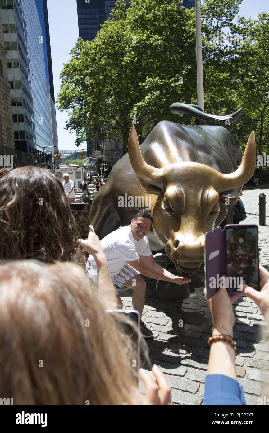 I turisti si allineano per scattare le loro foto con il famoso Wall Street Bull lungo Lower Broadway a Manhattan, New York City. Foto Stock