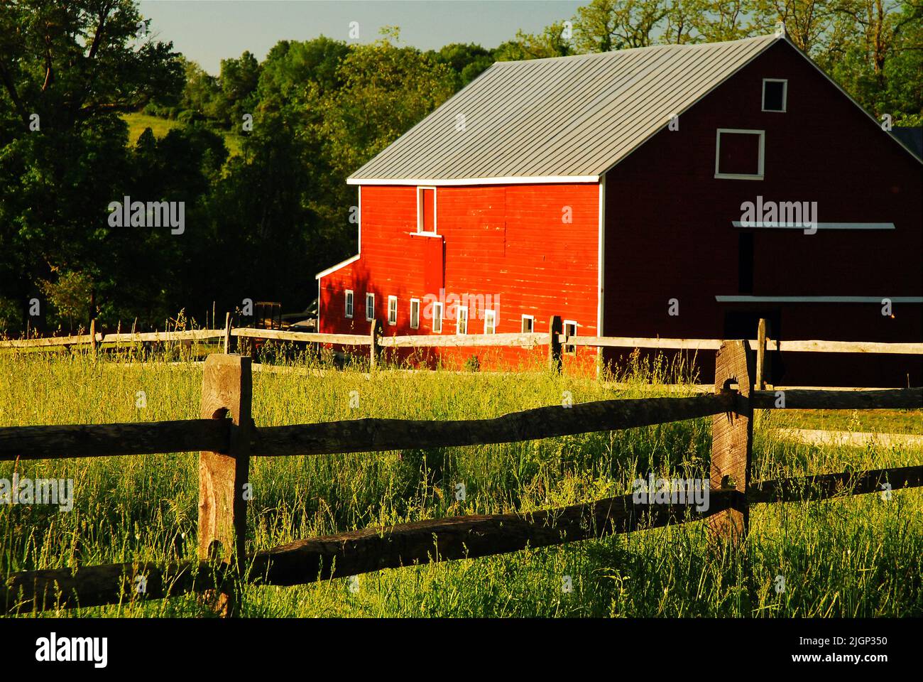 Un granaio rosso si trova dietro una barriera ferroviaria divisa che circonda un campo agricolo nella zona rurale della valle del fiume Hudson vicino a New Paltz Foto Stock