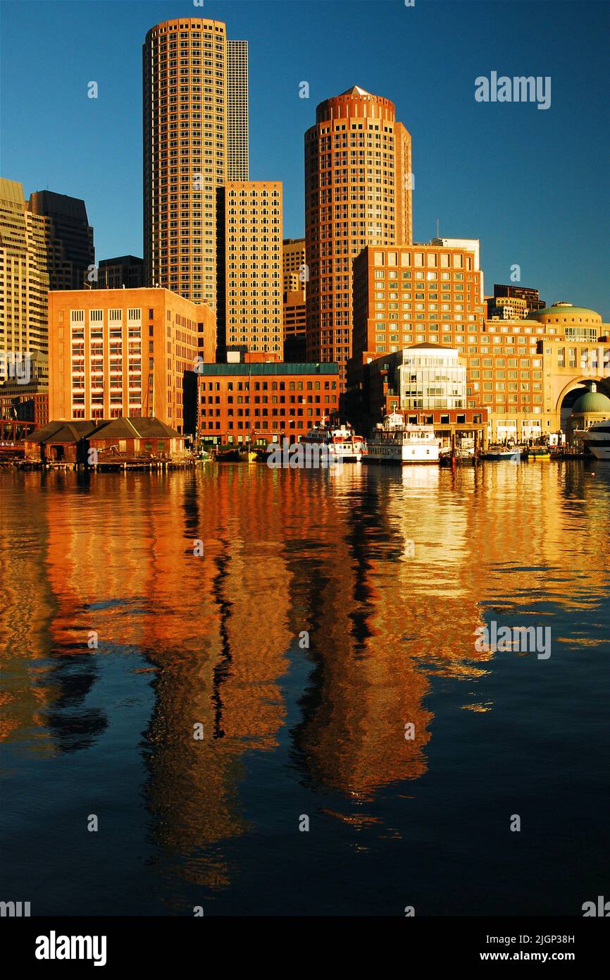 Lo skyline del Boston Financial District nel centro cittadino si riflette nelle acque del porto in una giornata tranquilla e tranquilla Foto Stock