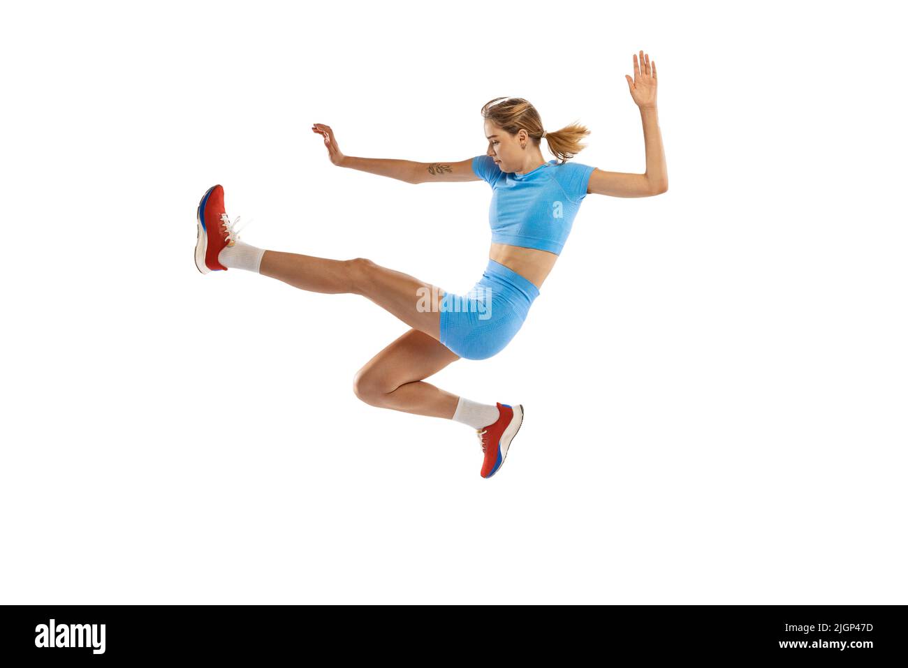 Tecnica a salto triplo. Studio di atleta femminile in sport uniforme salto isolato su sfondo bianco. Concetto di sport, azione, movimento, velocità. Foto Stock