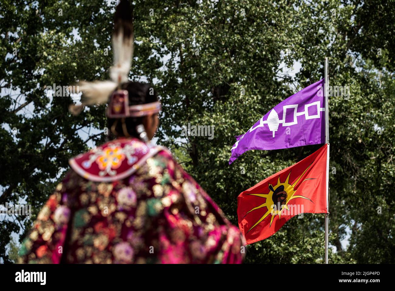 Durante il festival, un partecipante al Pow-Wow attende il suo turno di fronte alla bandiera del guerriero Mohawk e alla bandiera della Confederazione Iroquois. Foto Stock