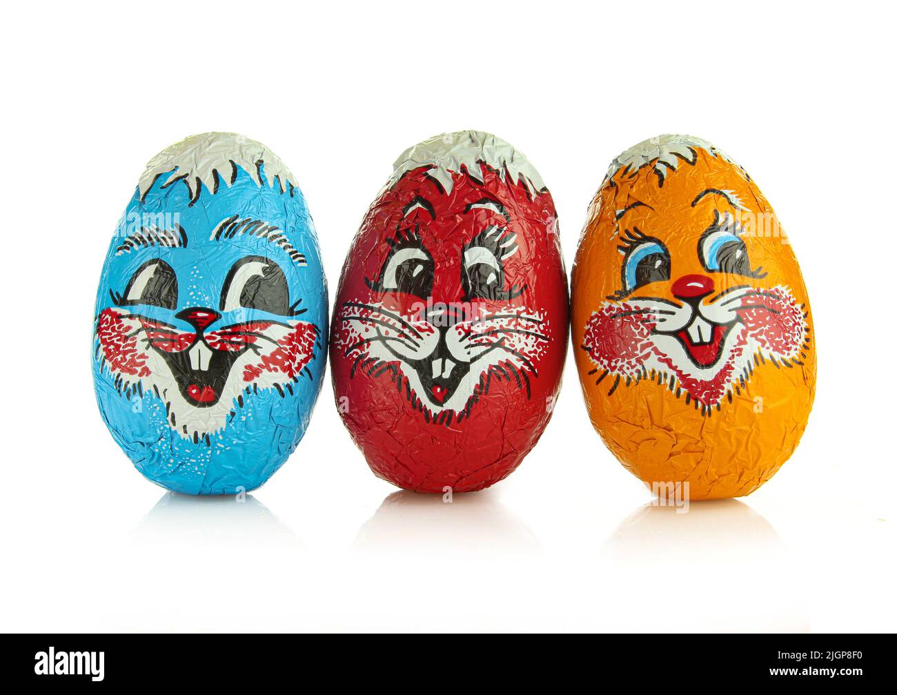 Rosso, blu e arancio foglia avvolto uova di cioccolato con facce sorridenti isolato su sfondo bianco. Vacanza pasqua tradizione Foto Stock