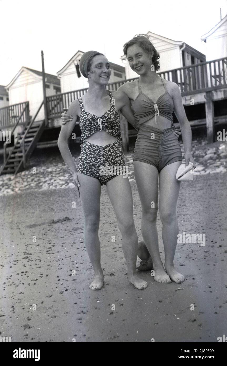 1940s, storica, due giovani donne che indossano ciascuna un costume da bagno in due pezzi dell'epoca in piedi sulla spiaggia per la loro foto, Ifracombe, Inghilterra, Regno Unito. Foto Stock