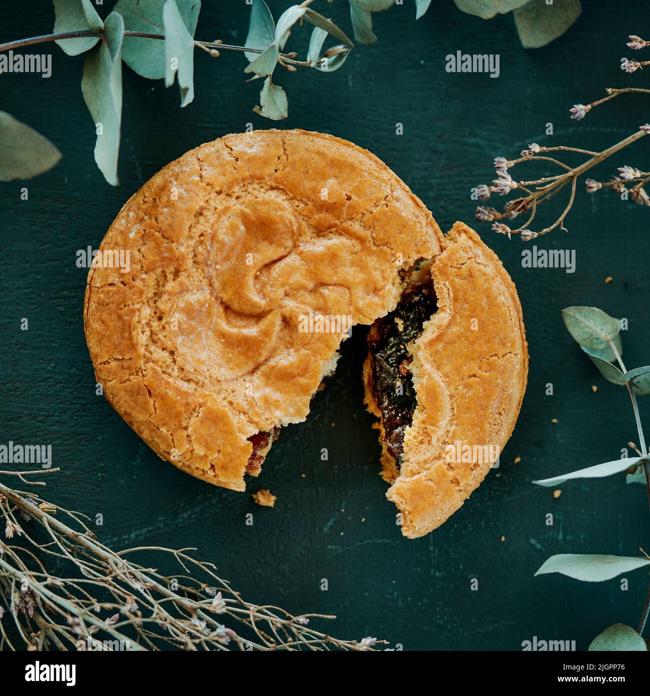 alto angolo di vista di un altopiano basco, tipico del paese basco francese, separato per mostrare il suo ripieno di marmellata di ciliegia, su una superficie verde scuro Foto Stock