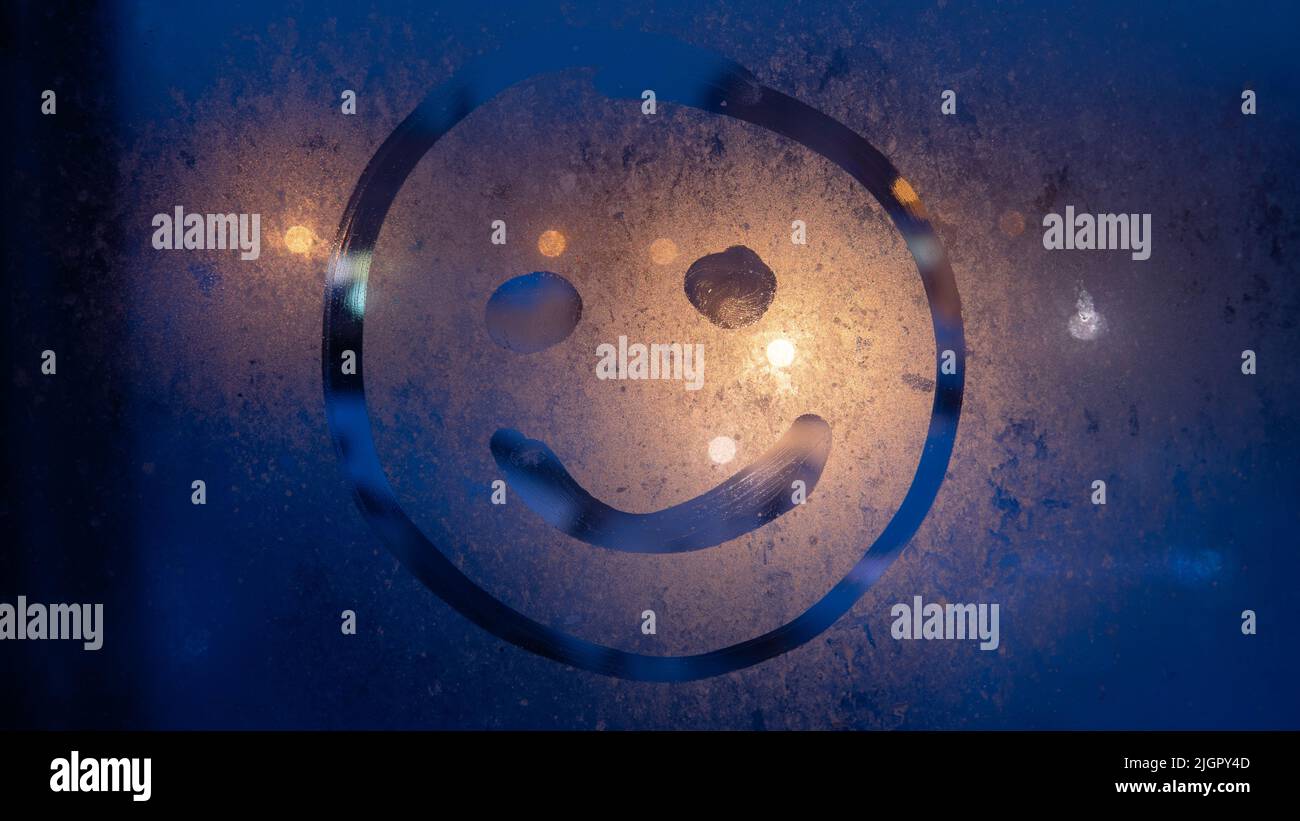 Happy emoji disegnate a mano sullo sfondo della finestra di vetro appannato. Happy Face firmi in primo piano. Concetto di stile di vita positivo. Messa a fuoco selettiva sulla foto. Bokeh di ni Foto Stock