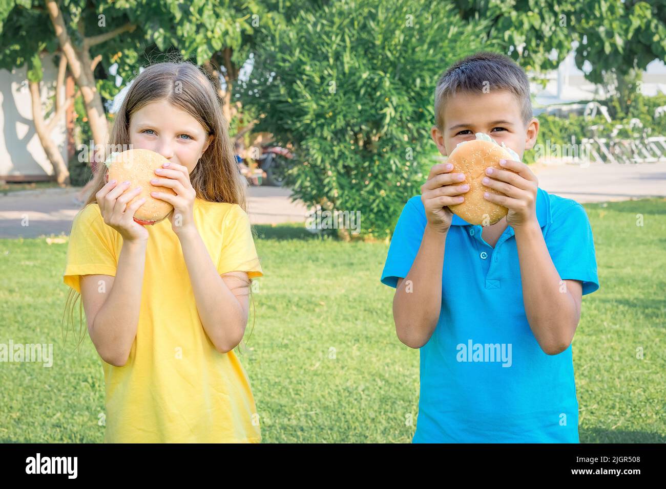 Gli scolari mangiano hamburger nel parco. Pranzo dopo scuola. Foto Stock