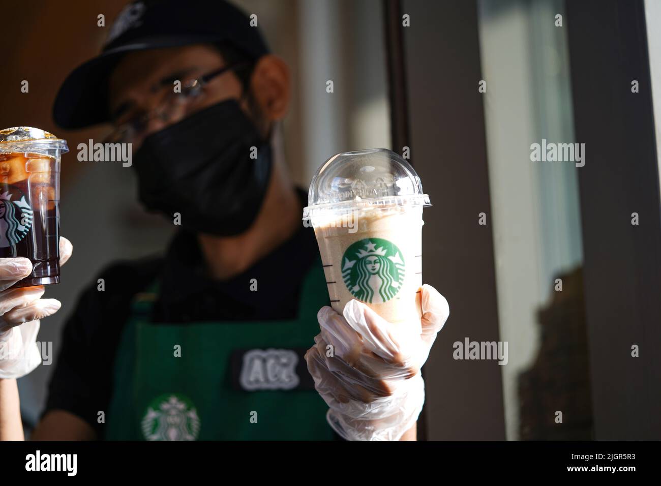 I lavoratori Starbucks consegnano gli ordini al drive-thru. Foto Stock