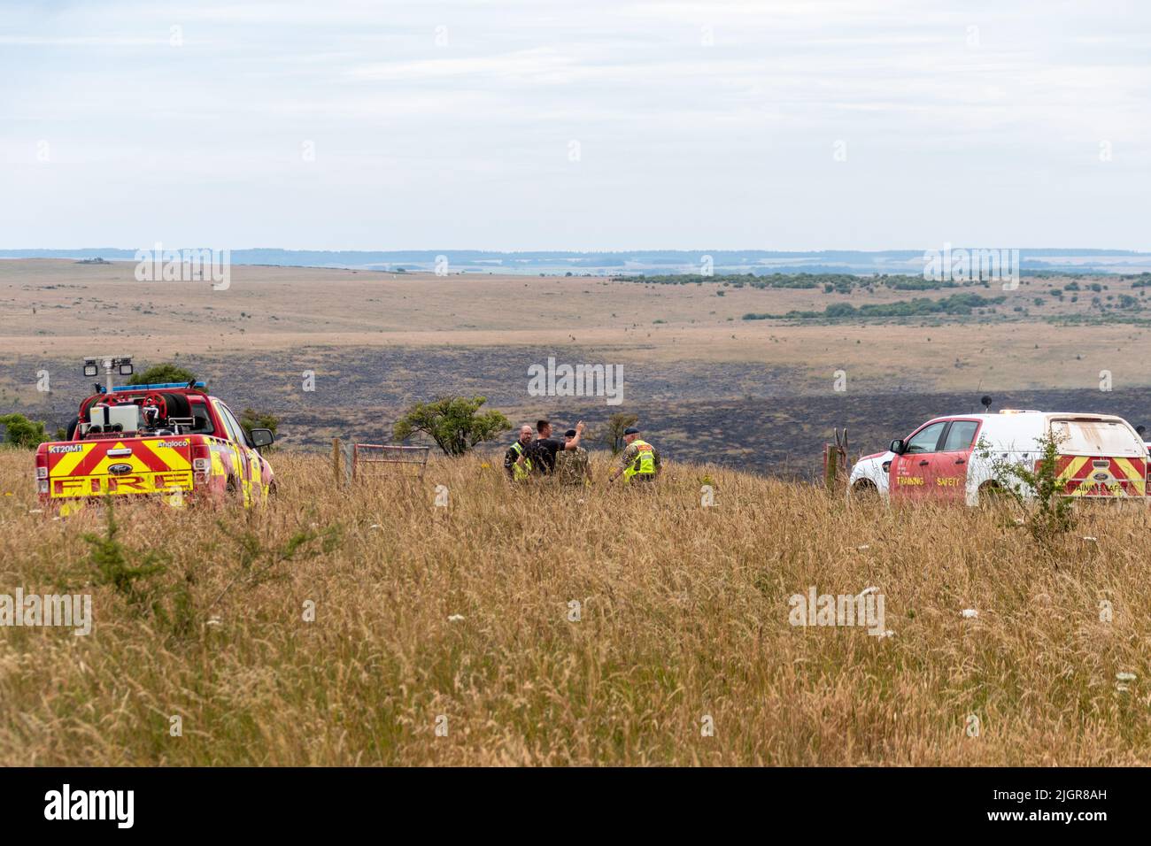 Salisbury Plain, Wiltshire, Inghilterra, 7th luglio 2022 il personale dei vigili del fuoco di Dorset e Wiltshire e i militari consultano con estese aree bruciate visibili in background Credit Estelle Bowden/Alamy News Foto Stock