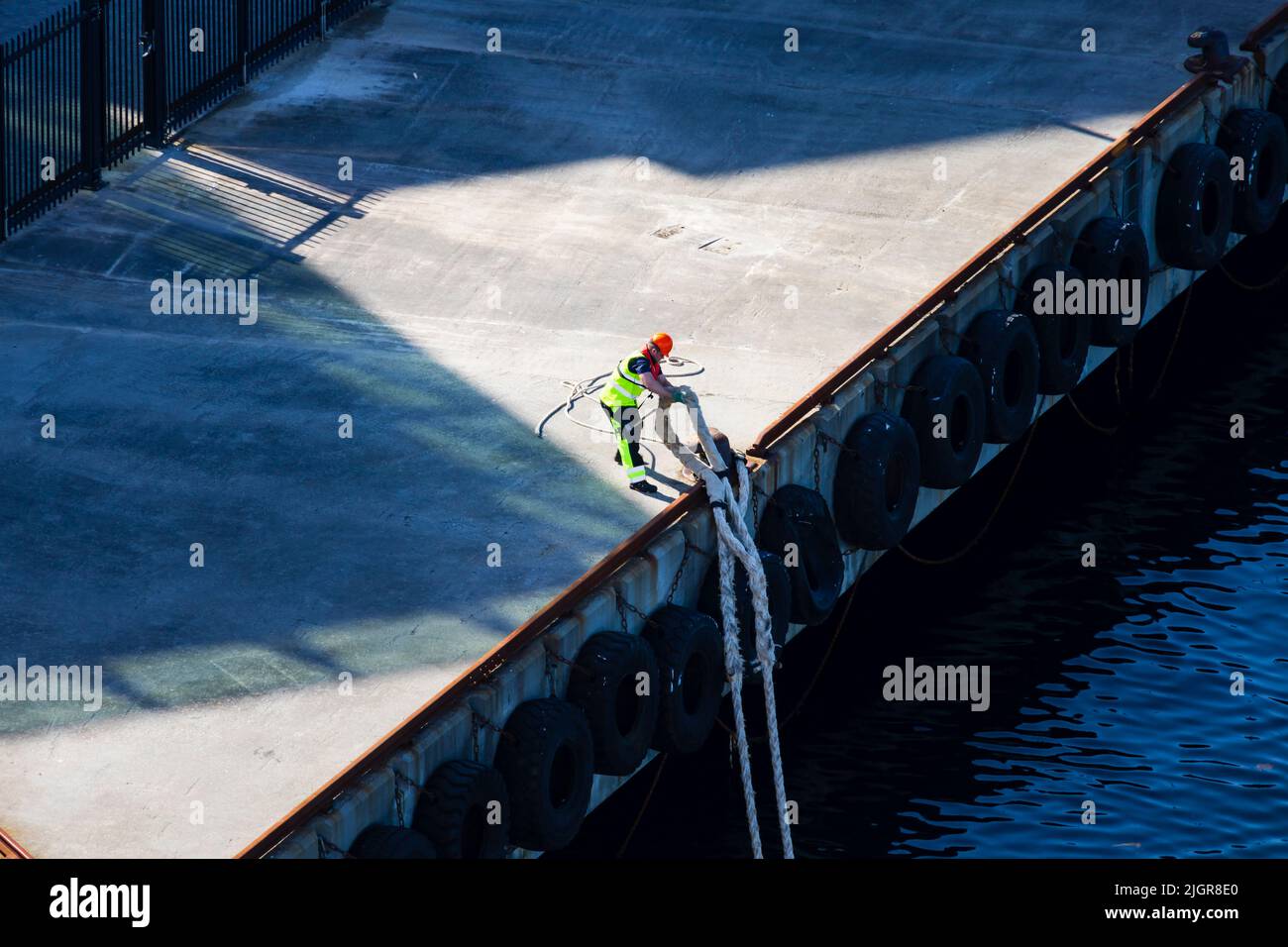 Stevedore, sul molo, raccoglie il falco della linea di ormeggio dalla nave da crociera P&o MS Iona, Stavanger, Norvegia. Foto Stock