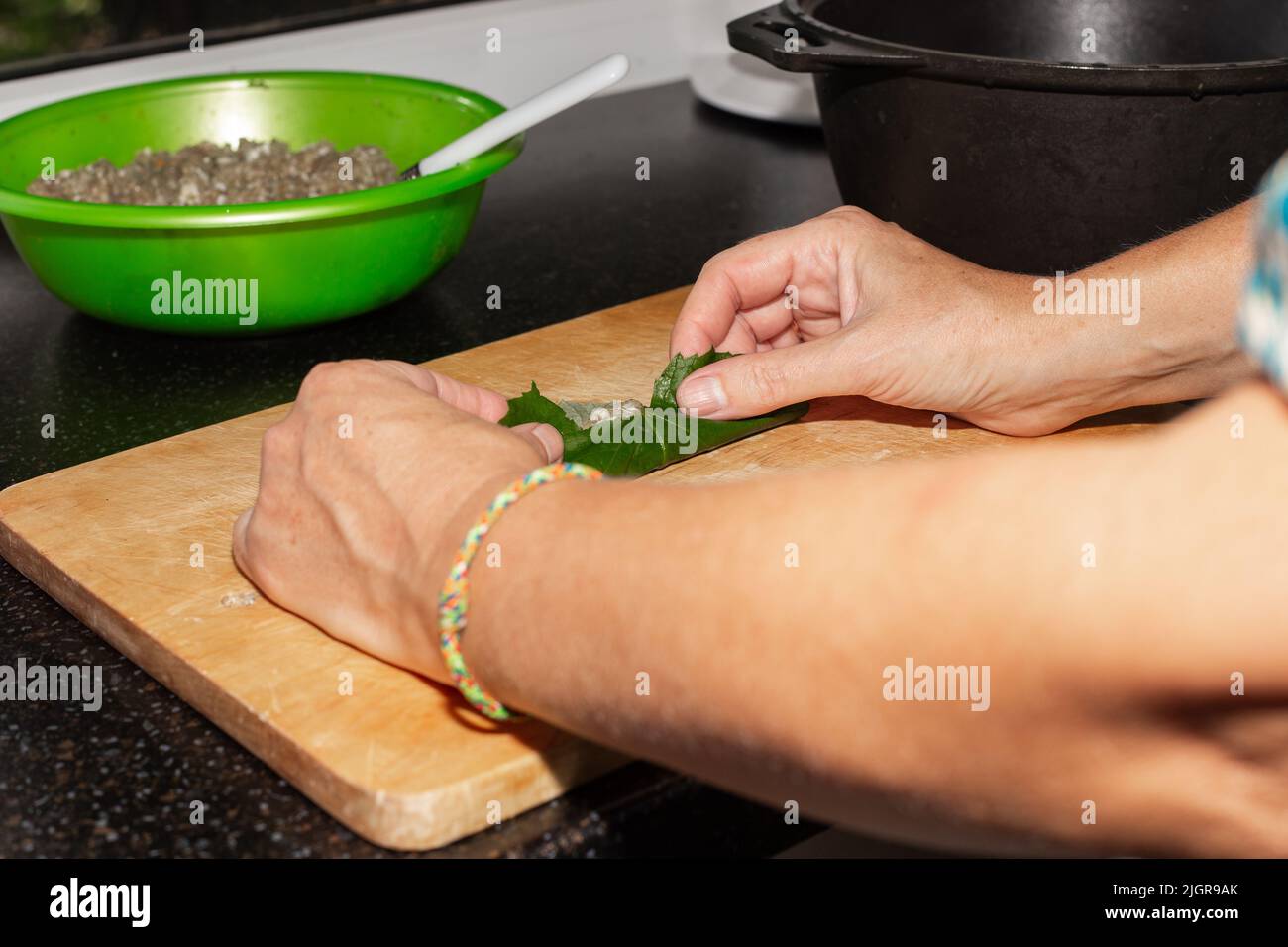 Una donna infila foglie d'uva con carne. Cucina caucasica piatto dolma. Foto Stock