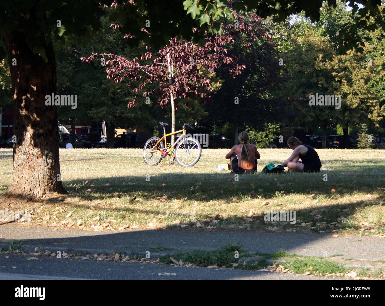 Un parco con due persone e bicicletta sull'erba a East Vancouver, British Columbia, Canada Foto Stock