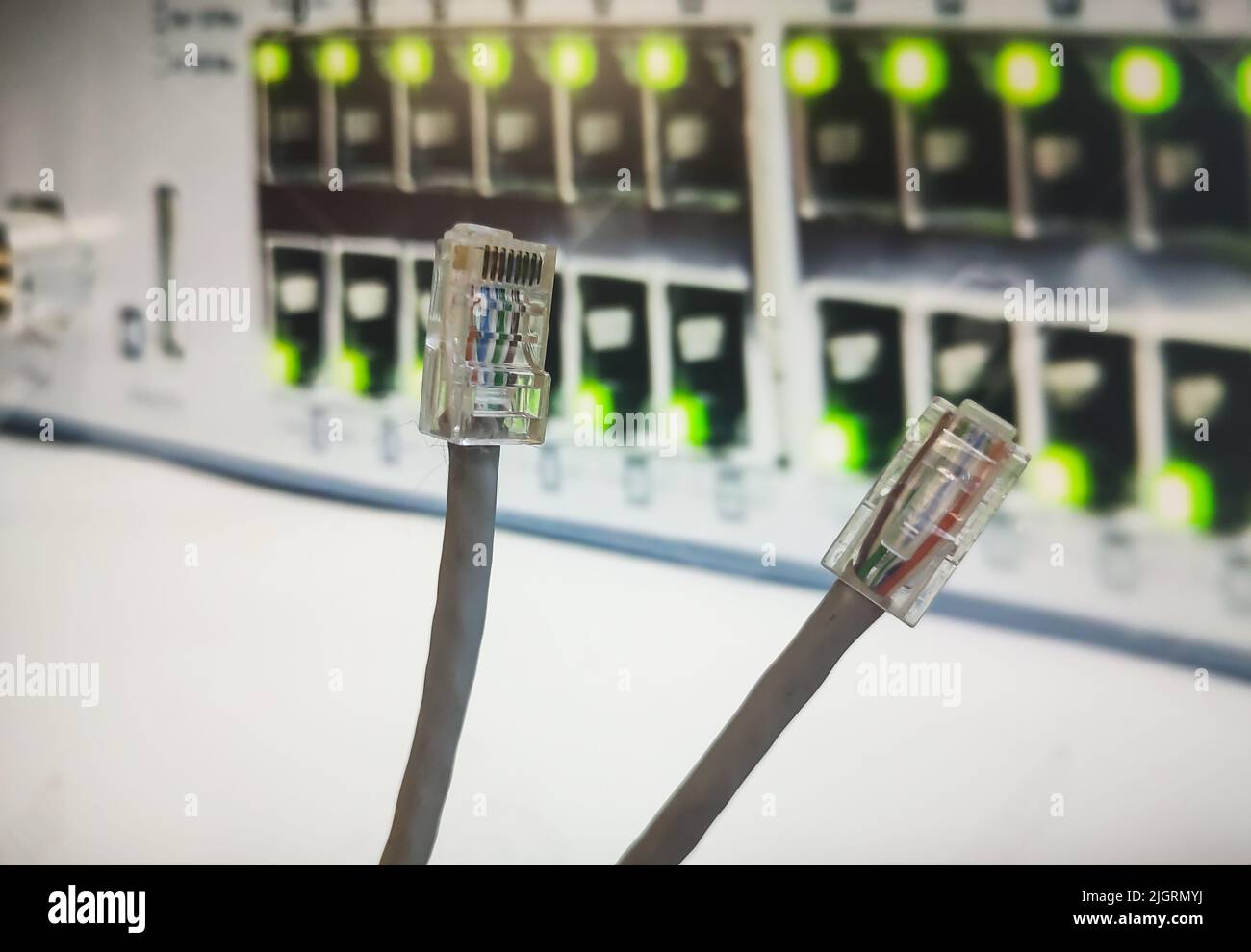 RJ45 cime dei cavi davanti a un centralino. I RJ45 pin vengono utilizzati in una tabella di rete per collegare l'apparecchiatura Internet Foto Stock