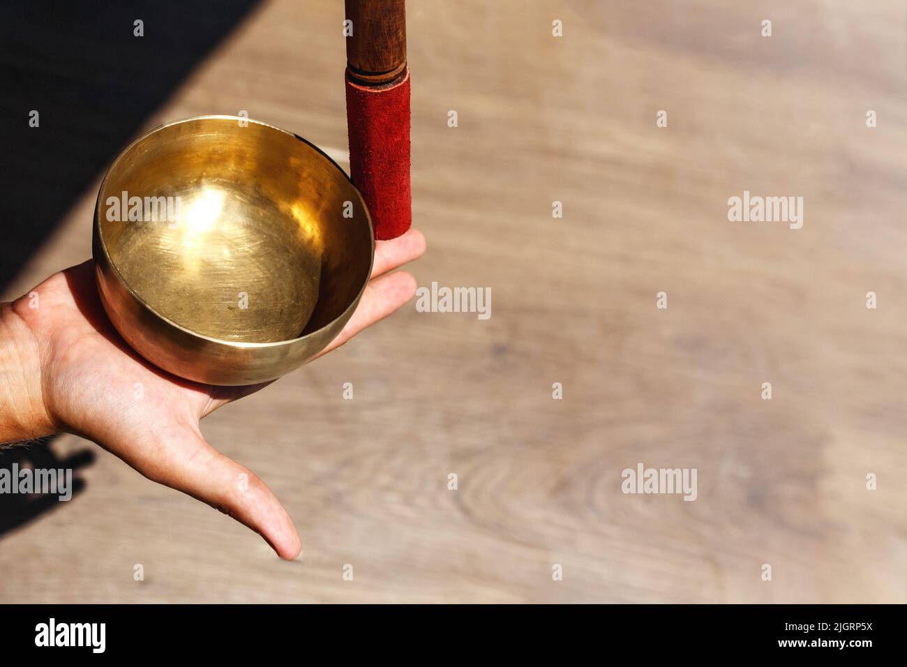 L'uomo mani usando la ciotola di canto nella terapia healing del suono all'aperto, primo piano. Foto Stock