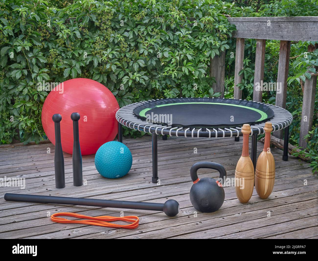 home gym concept - palle svizzere e slam, kettlebell in ferro, mini trampolino, banda di resistenza, club d'acciaio, Macis di acciaio e randelli indiani di legno su un backy Foto Stock