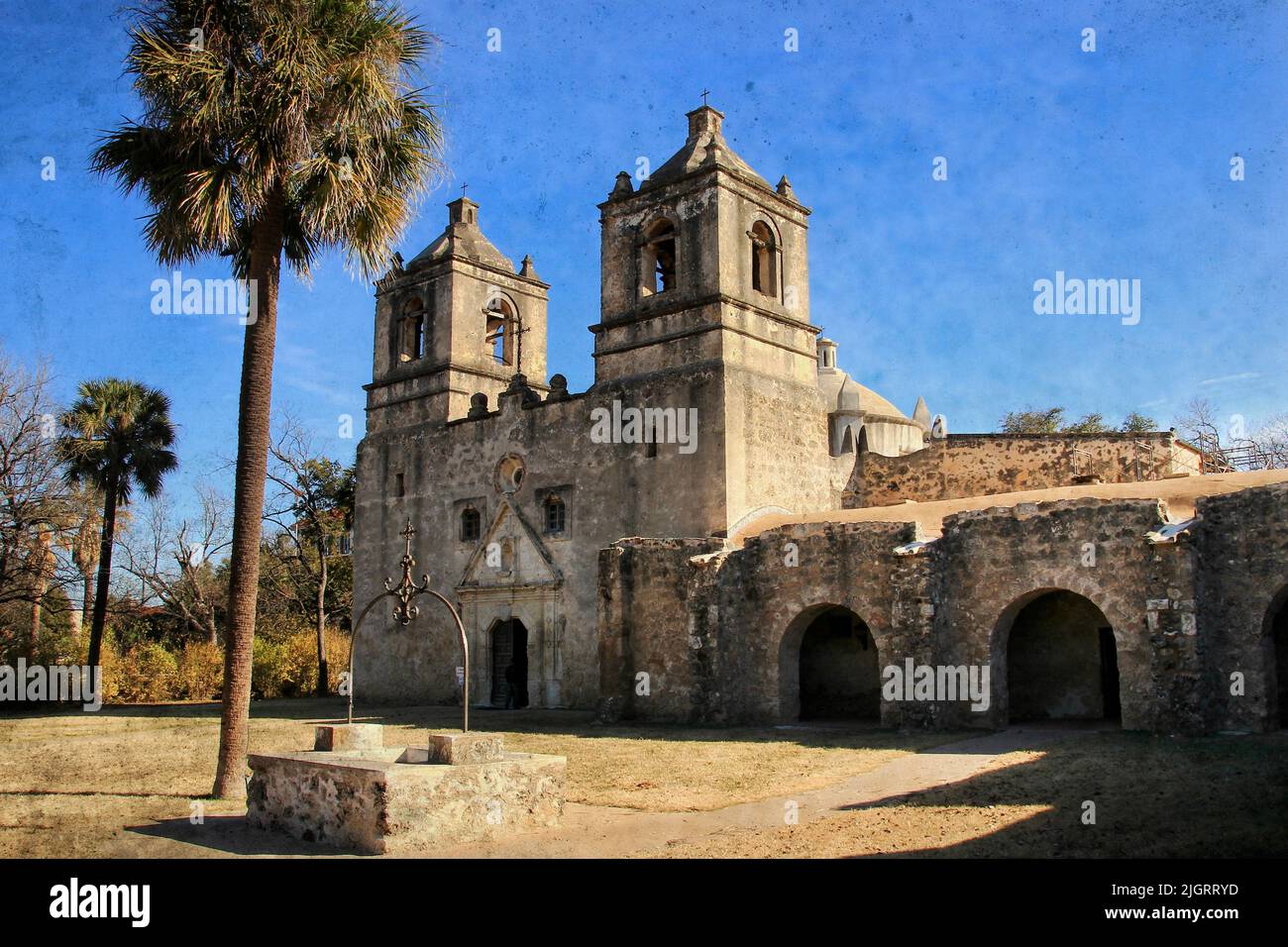 Mission Concepcion, San Antonio, Texas: Questa è una foto testurizzata di una vecchia missione spagnola in pietra, con cieli blu, archi, e un pozzo. Foto Stock