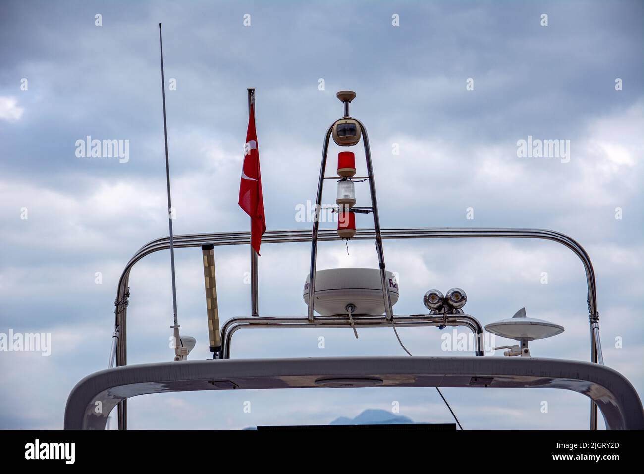 La parte superiore dello yacht con la bandiera della Turchia e il faro rosso contro il cielo blu con le nuvole Foto Stock