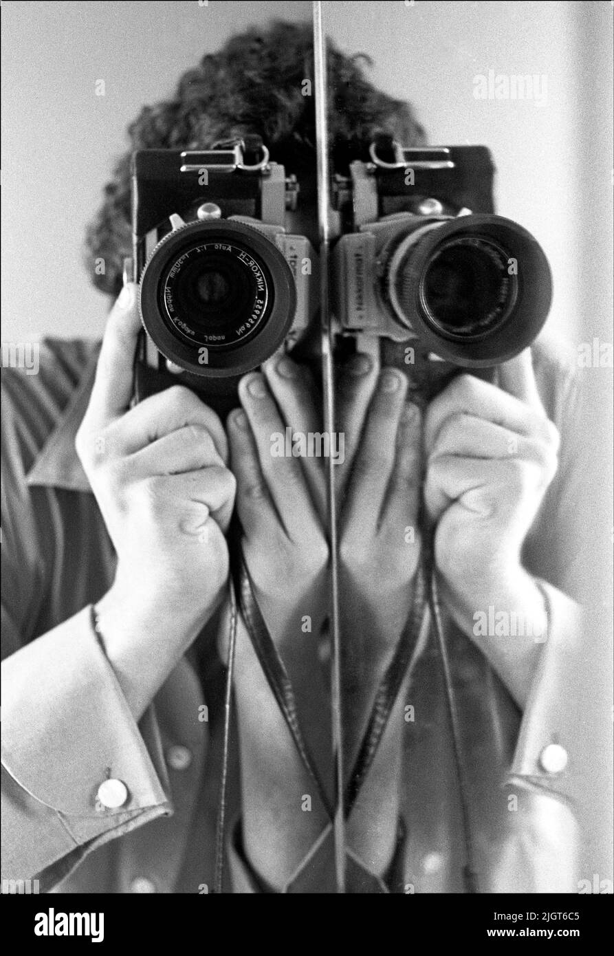 Autoritratto in bianco e nero con specchio split e telecamera Nikkormat. Foto Stock