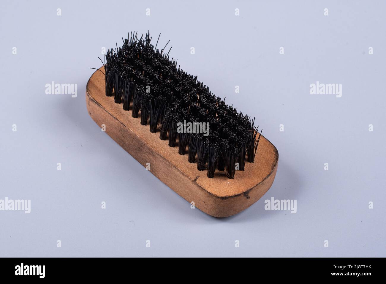 spazzola lustrascarpe con manico in legno su sfondo blu chiaro Foto Stock