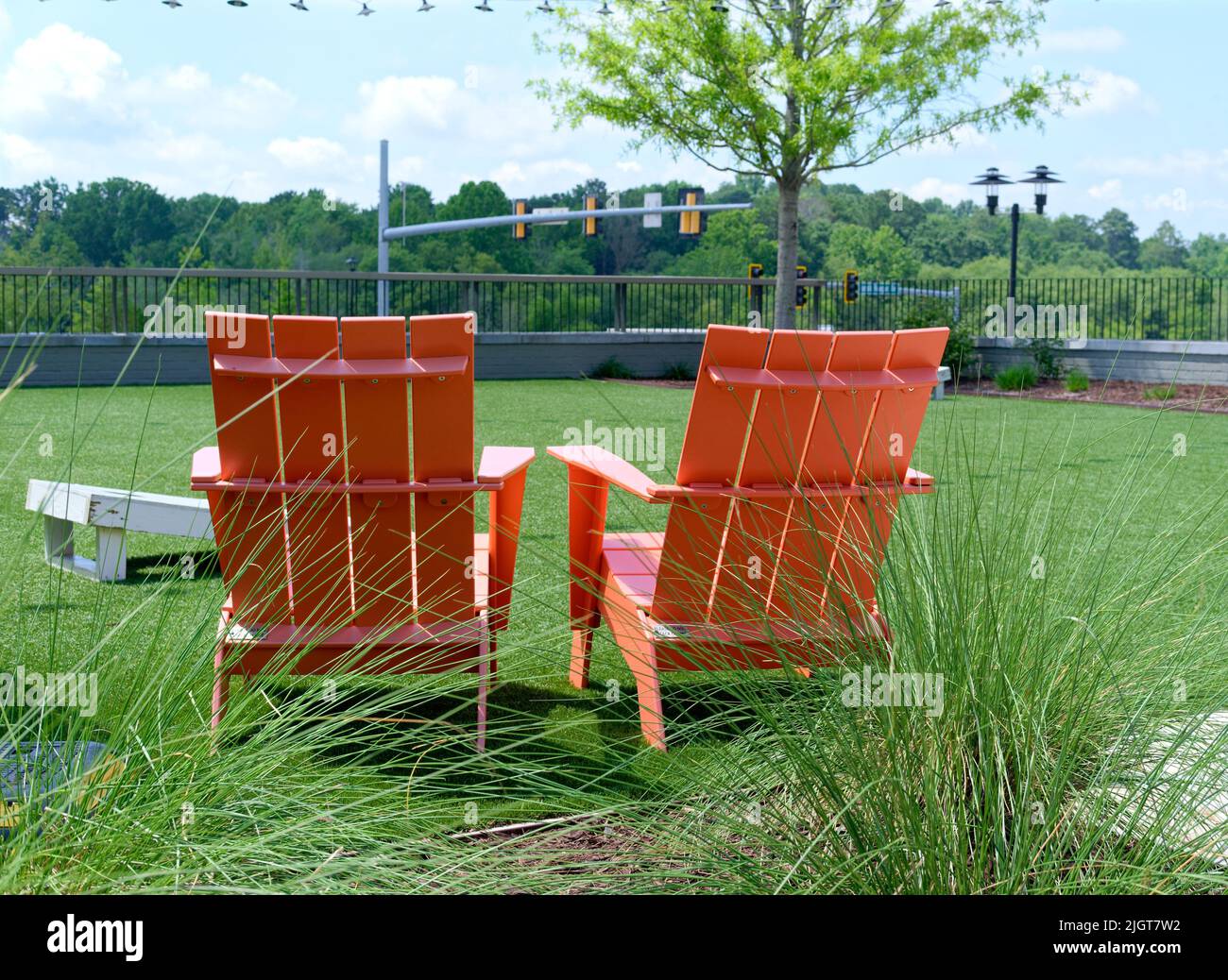Sedie Adirondack arancione nel parco Foto Stock