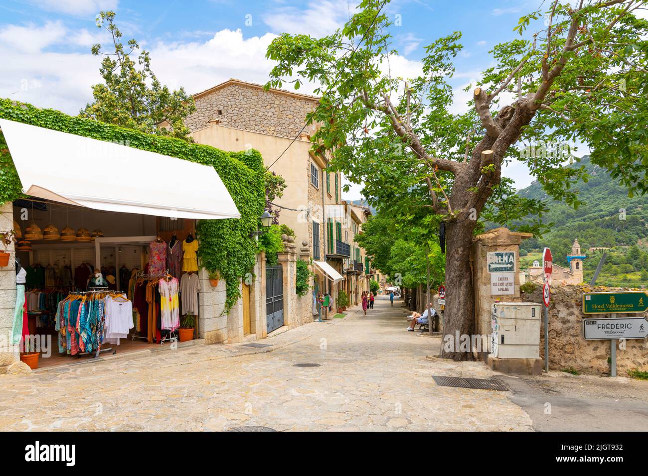 Una delle molte pittoresche strade alberate di negozi e caffè nel villaggio collinare di Valldemossa, Spagna, sull'isola di Mallorca, Spagna. Foto Stock