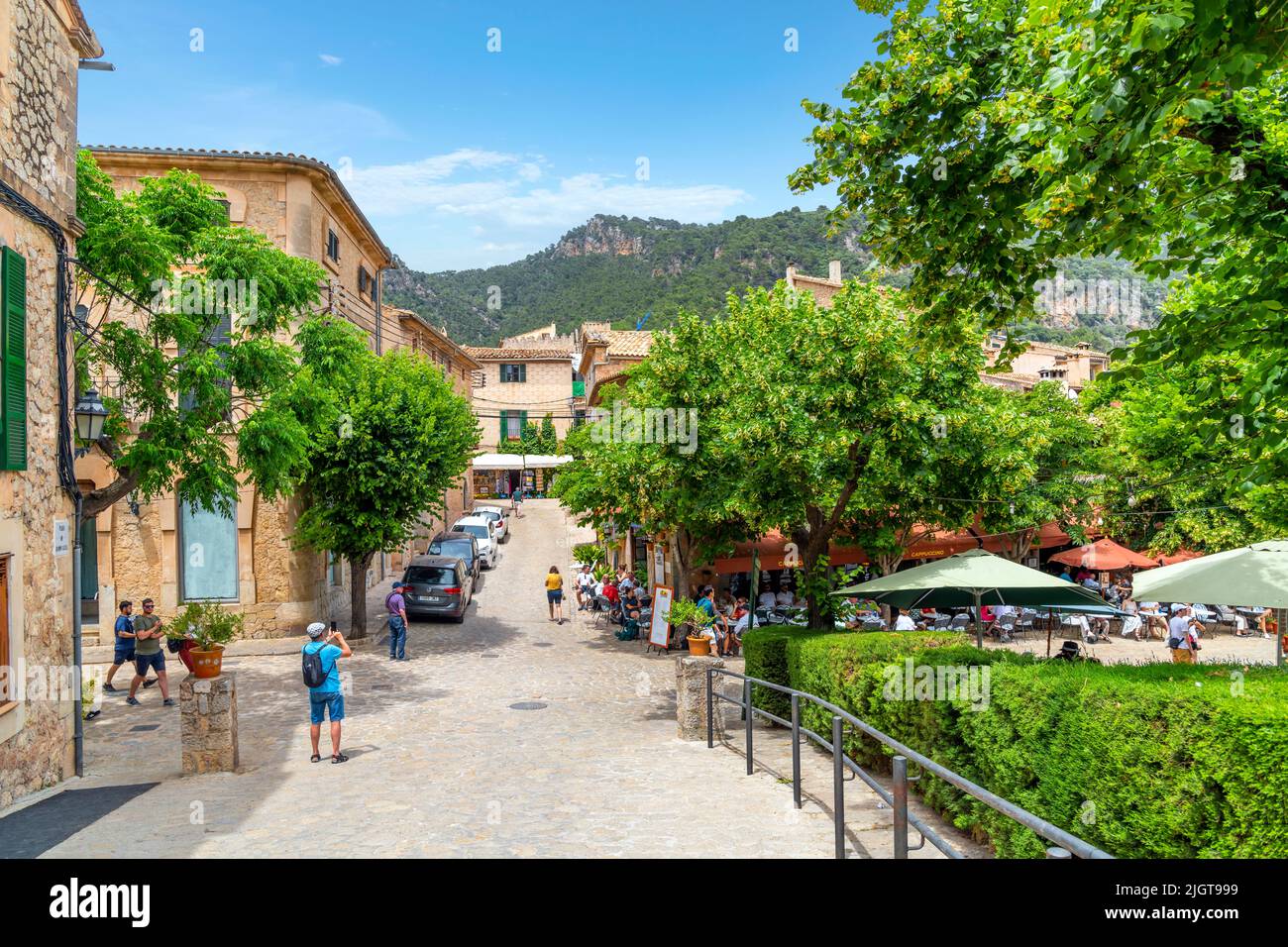 Una delle molte pittoresche strade alberate di negozi e caffè nel villaggio collinare di Valldemossa, Spagna, sull'isola di Mallorca, Spagna. Foto Stock