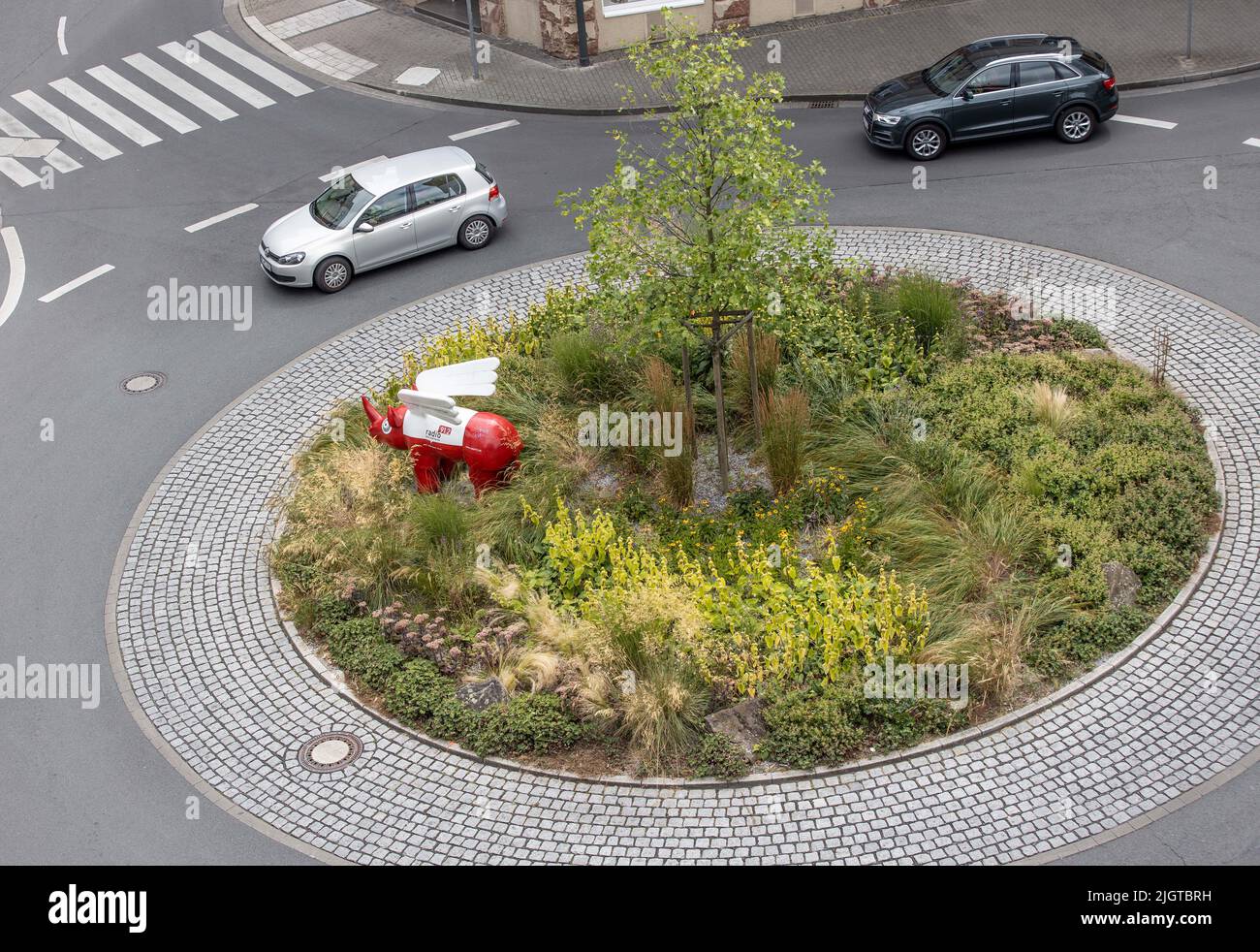 Dortmund, Germania. 11th luglio 2022. Una piccola isola trafficata nel centro della città - un piccolo albero e un rinoceronte rosso si erigono su di esso per scopi pubblicitari per una stazione radio locale. Il piccolo punto verde si trova su Google come un presunto 'Brauer Memorial Park'. La città di Ruhrgebiet presuppone che l'ingresso 'parco' provenga da un utente di Google che scherzava. Credit: Dieter Menne/dpa/Alamy Live News Foto Stock