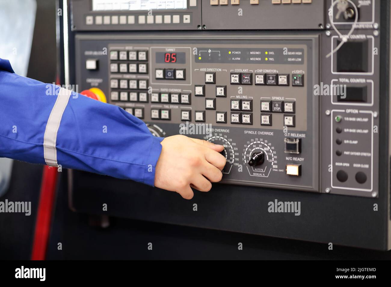 Il lavoratore cambia il controllo di avanzamento della macchina di tornio CNC. Messa a fuoco selettiva. Foto Stock