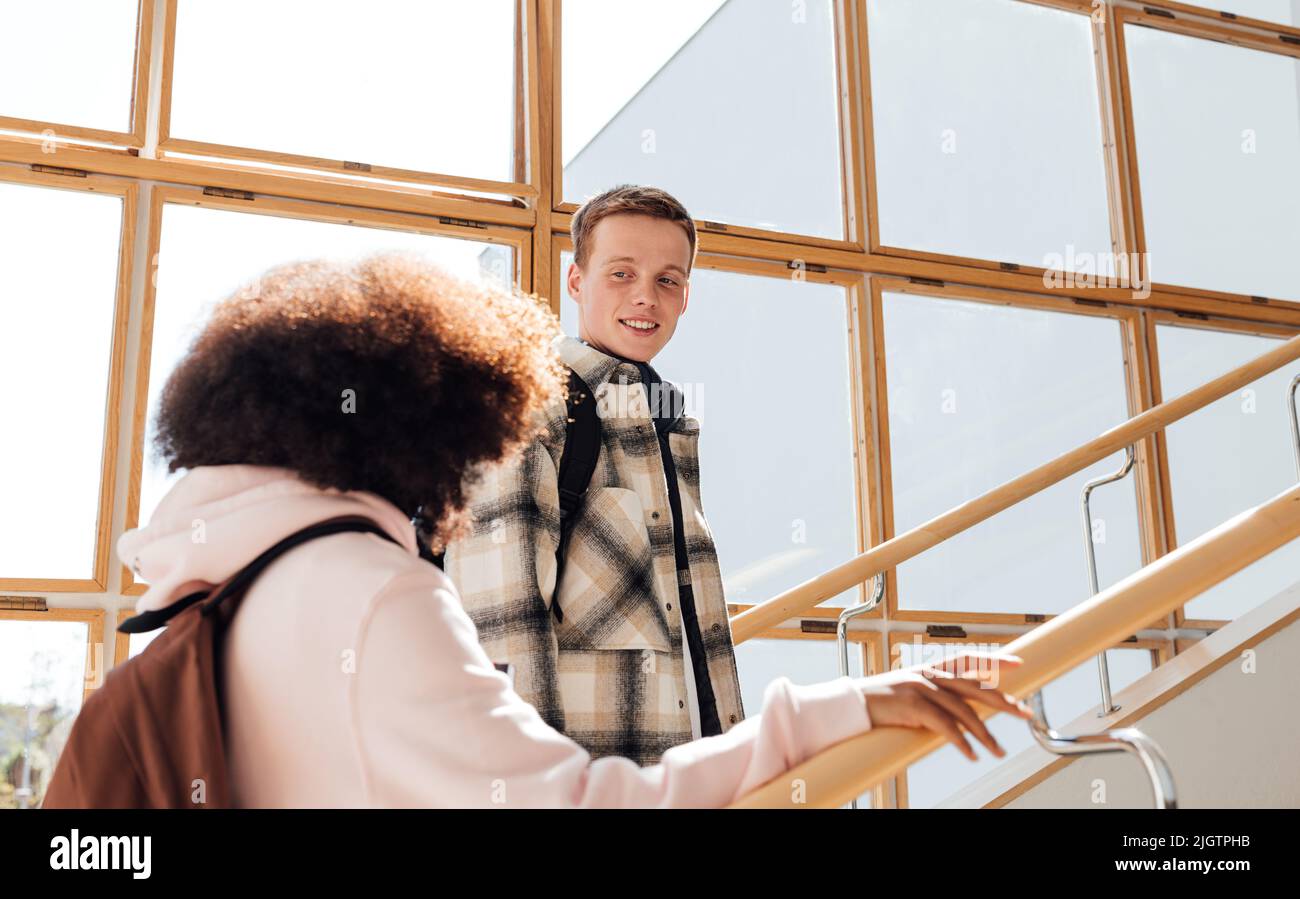 Due compagni di classe sono sulle scale. Ragazzo guardando una ragazza mentre salendo le scale. Foto Stock