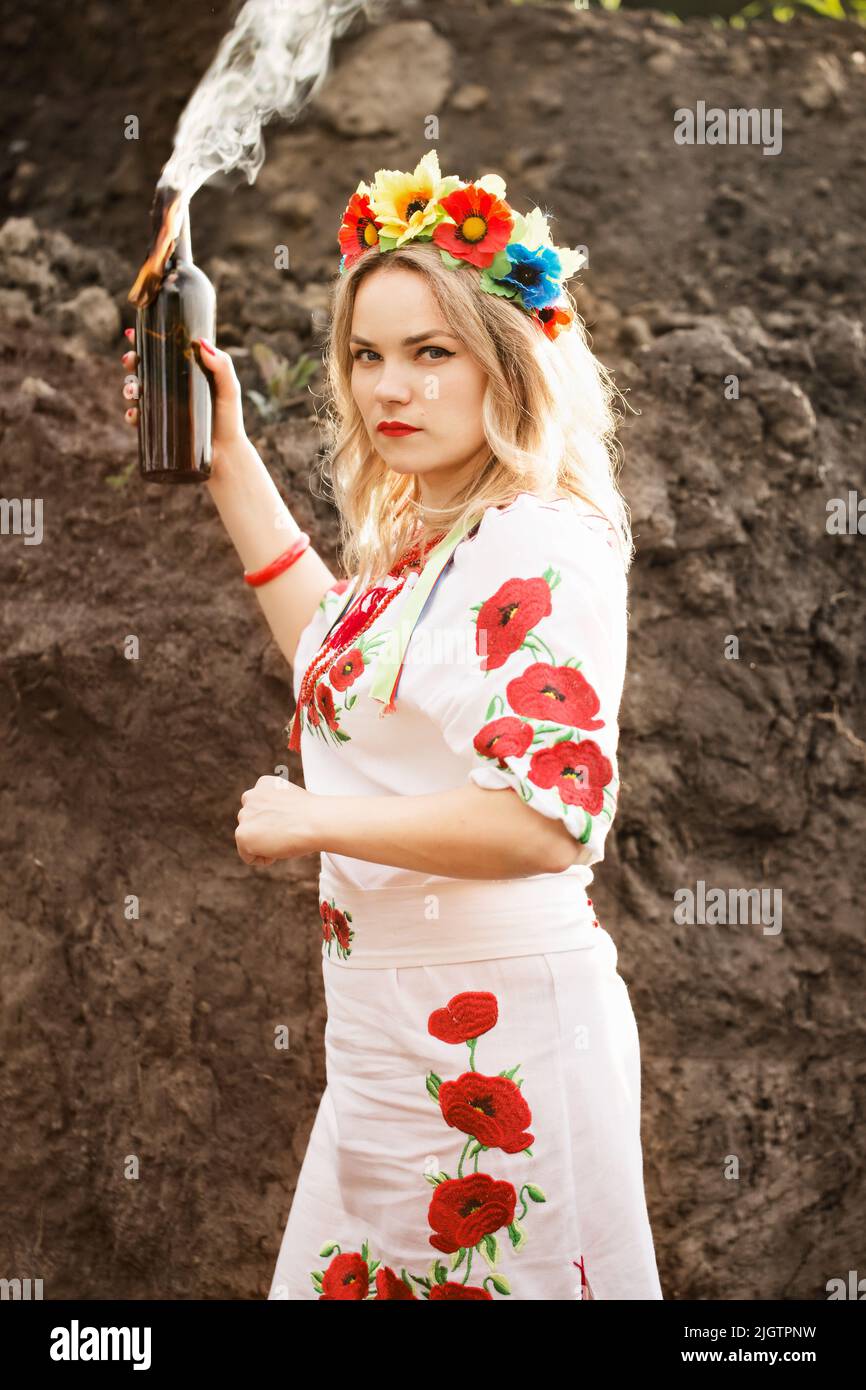 Una ragazza in un abito ricamato nazionale ucraino con un cocktail Molotov nelle sue mani, un simbolo dell'Ucraina che si difende contro gli invasi russi Foto Stock